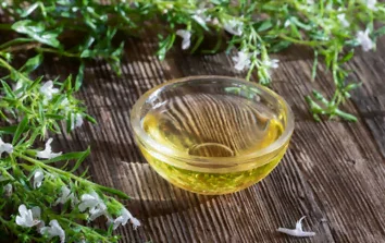 Sarriette en fleurs autour d'un petit pot de liquide